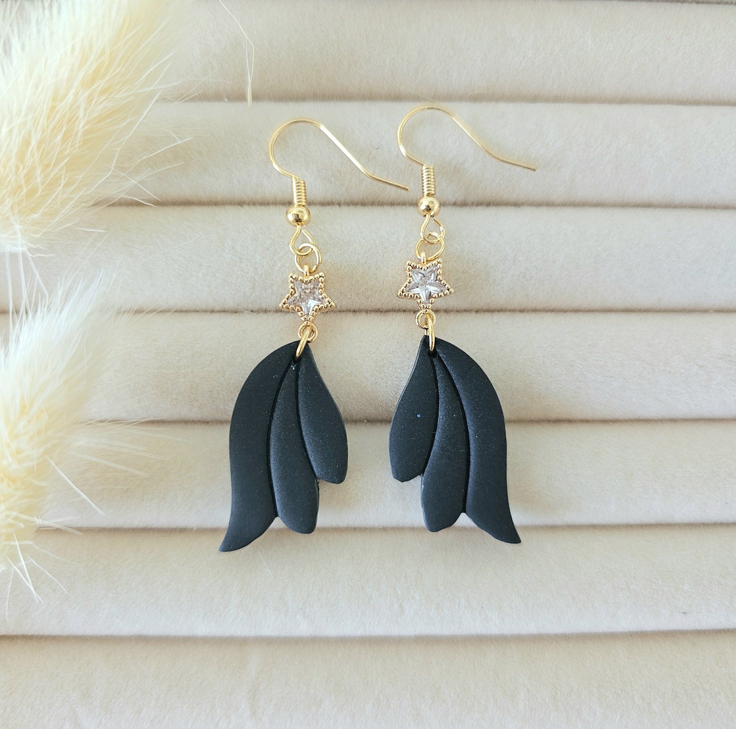 Black leaf-shaped earrings with gold hooks and star embellishments