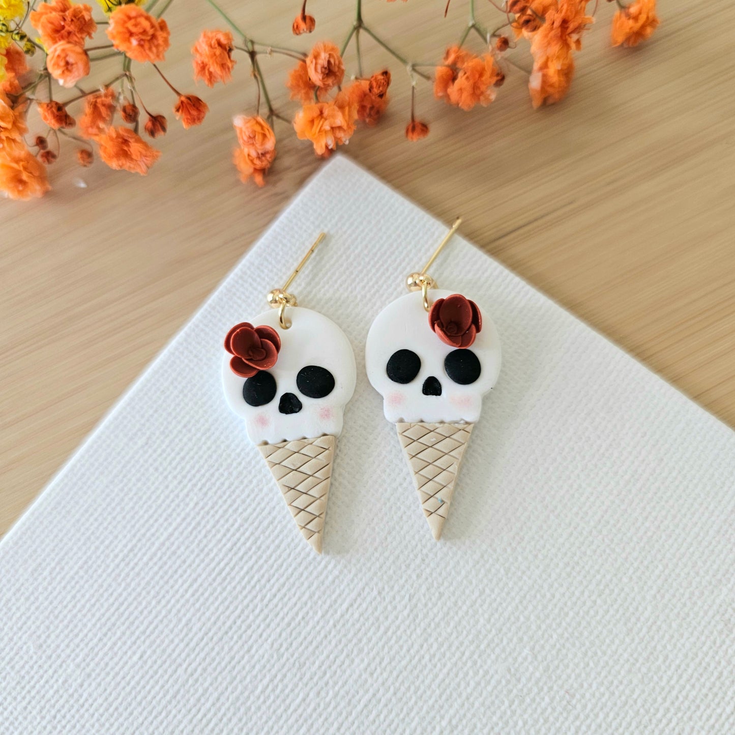 A pair of earrings designed as ice cream cones with skull decorations.