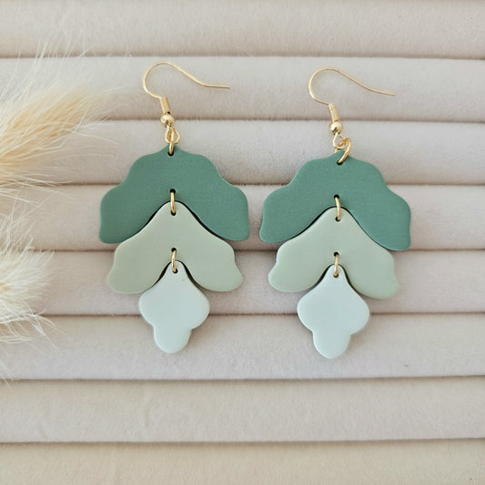 Pair of green tiered earrings on a light wooden surface