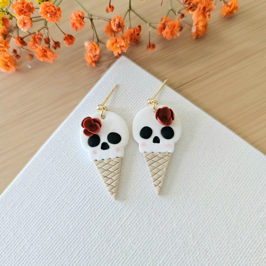 A pair of earrings designed as ice cream cones with skull decorations.