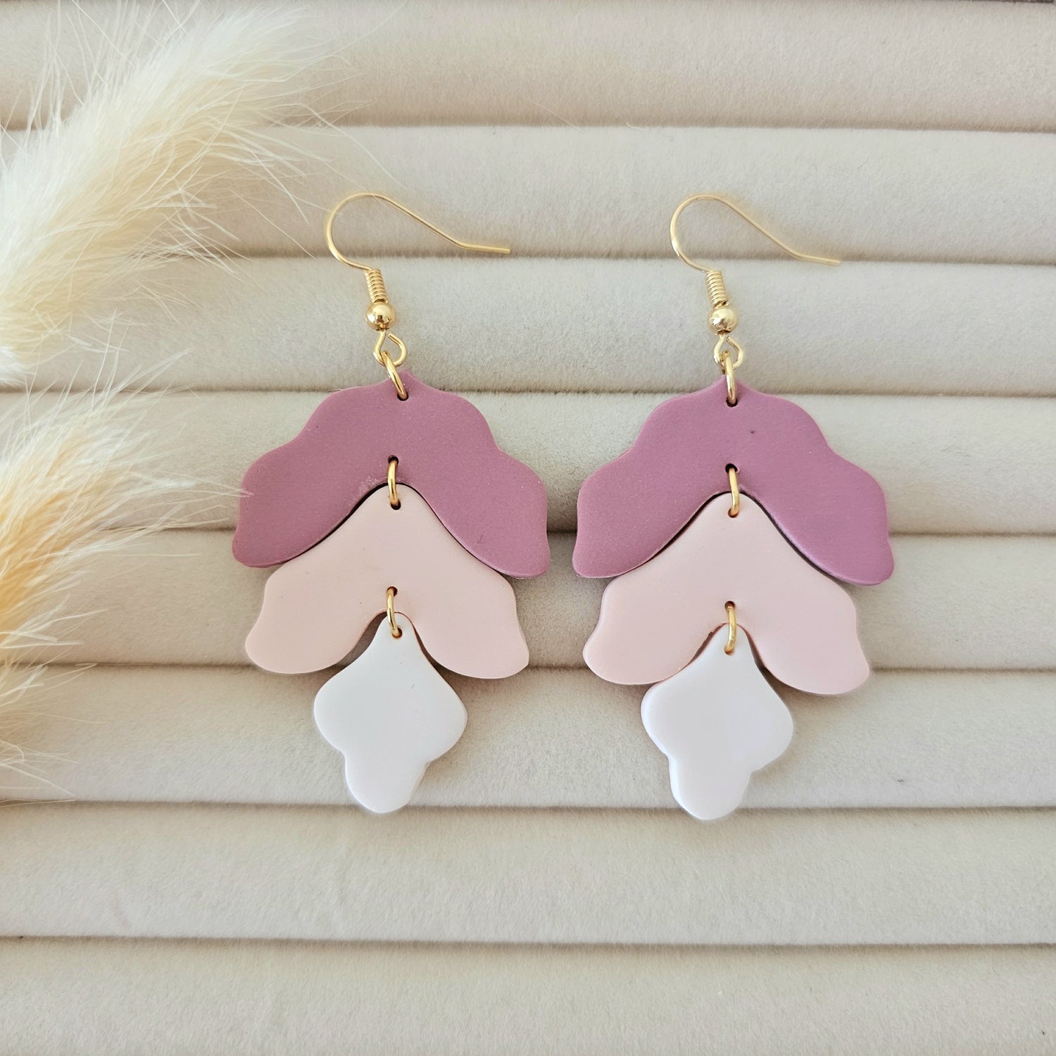 Pair of pink and white layered earrings on a wooden surface